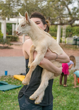 Goat Yoga with young woman holding goat like a baby