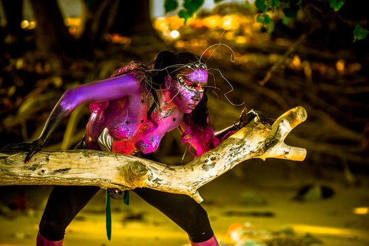 Woman in bodypaint playing on the Mangrove beach