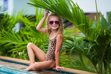 Smiling cute little girl in sunglasses in pool in sunny day