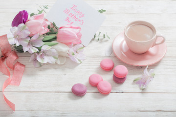 Tulips and cup of coffee with dessert on white background. Concept woman's or mother's day top view