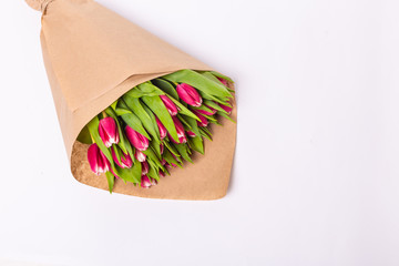 Bouquet of a pink tulips in a package of kraft paper, isolated on white background