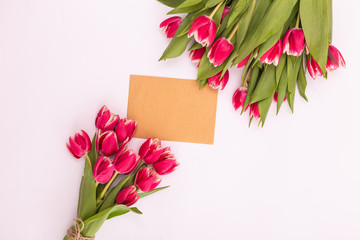 A bouquet of beautiful tulips and a card for text on a white background fork on top. Mother's day background, International Women's Day, birthday. Holiday, give.