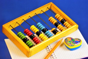 Abacus for teaching children to count. Abacus device for performing arithmetic calculations, notebook for records, colored pencil and pencil sharpener in the form of a heart.