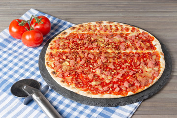 Pizza on a blue napkin with red tomatoes.