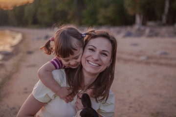 Mother and daughter playing on the beach at sunset. The concept of a happy friendly family.