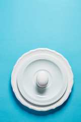White egg on the blue background in center. Design, visual art, minimalist top view copy space