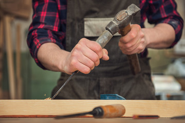 The worker makes measurements of a wooden board with ruler.