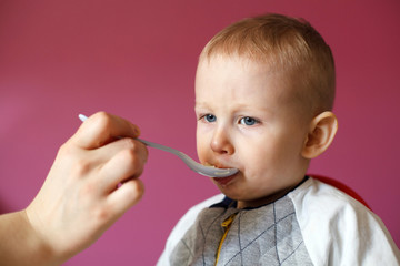 Mom feeds her beautiful baby with a spoon. Healthy Chicken Soup