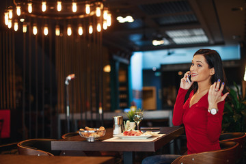 Young woman on breakfast talking on the phone in a restaurant