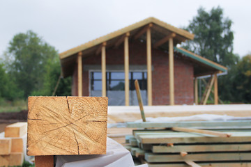 Part of the wooden beam on the background of the house under construction