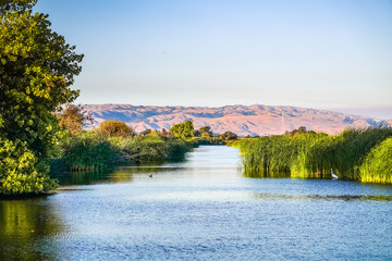 Ponds at sunset in Coyote Hills Regional Park; on the background smoke from Soberanes fire is visible, San Francisco bay area, California - obrazy, fototapety, plakaty