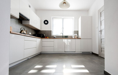 Minimal white kitchen interior with wooden countertop. Real photo