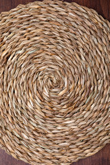 Empty trivet Of natural fibers. On dark wood background. Concept to include your food and your text.