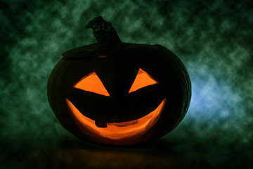 Halloween Pumpkin. Supernatural atmosphere. The green fog covers the pumpkin. Light from a burning candle