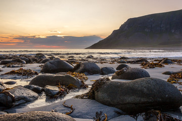 sunset on Unstad beach surrounded by mountains in Lofoten in Norway
