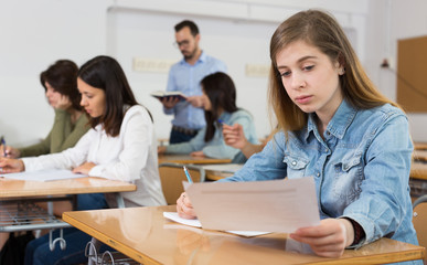 Fototapeta premium Smiling schoolgirl is learning and answering the question on paper