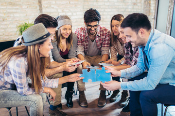 Businesspeople joining puzzle pieces in office. Indoor team building activities