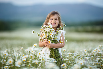 Little cute girl in a field of camomile flowers