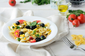 Pasta with cherry tomatoes, olives and corn on white background
