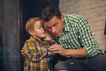 Young handsome father and his little stylish son at barbershop waiting for barber