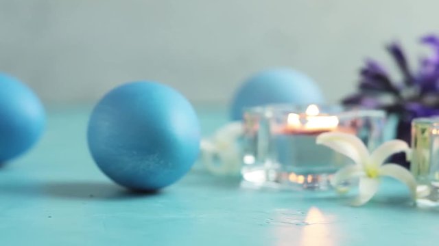 Blue easter eggs, candles and white hyacinth on blue concrete table surface background, copy space for you text. Festive background. Happy Easter greeting card.