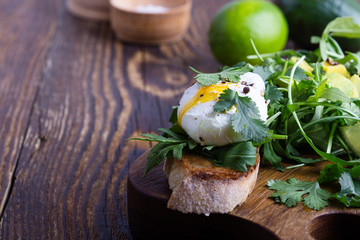 Vegetarian sandwich  with  poached egg, avocado, arugula  on toasted bread, healthy breakfast or snack