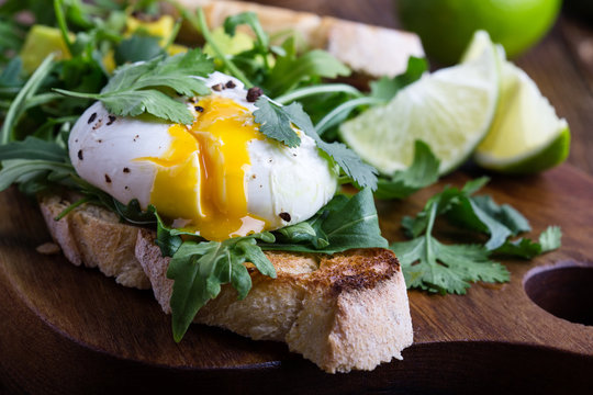 Vegetarian sandwich  with  poached egg, avocado, arugula  on toasted bread, healthy breakfast or snack