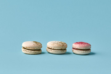 White macarons cake with colorful powder, top view, flat lay, sweet macaroon on blue background.