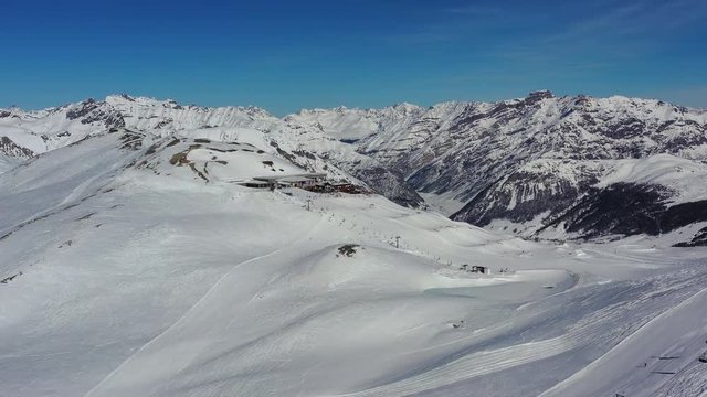 Aerial view of alpine skiers skiing downhill on ski slopes, hills covered with snow - Alps mountains in winter from above, ski resort Livigno, Italy, Europe