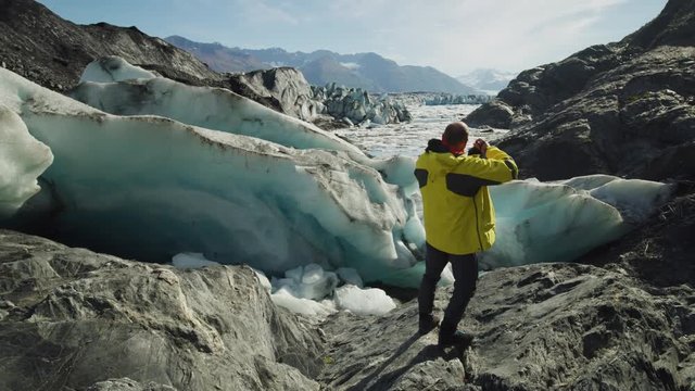 Slow motion of man walking on glacier and photographing scenic view,  / Palmer, Alaska, United States