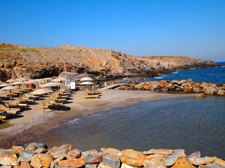 Waves breaking on the coast. Beach, sun beds and umbrellas, sea, waves, foam in the Greek resort....