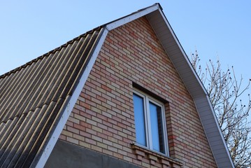 brown brick attic with a window against the blue sky