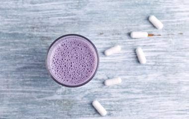 Fototapeta na wymiar Glass of Protein Shake with milk and blueberries and BCAA amino acids in background. Sport nutrition. Rustic wooden background. Top view. Copy space. 