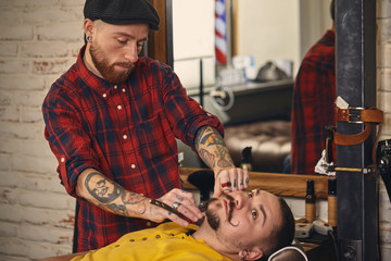 Client during beard shaving in barber shop