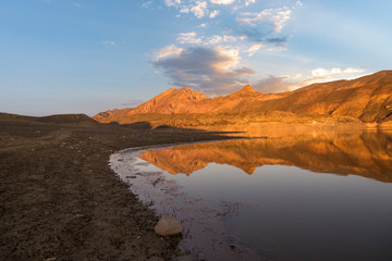 Beautiful sunset landscape. Bright sunlight on a mountain lake, the mountains  reflected in the water. Armenia.