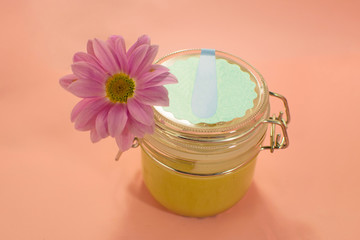 Sugar paste for depilation. Shugaring. Removing hair. Cosmetics. Honey in jar with flower on Living Coral background.