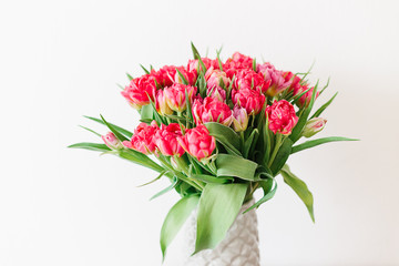 A bouquet of pink red white peony tulips in a gray modern vase on wooden tabel