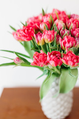 A bouquet of pink red white peony tulips in a gray modern vase on wooden tabel