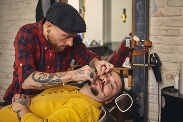 Client during beard shaving in barber shop