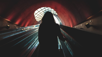Woman standing in a modern escalator tunnel with big window