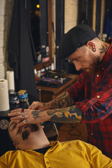 Client during beard shaving in barber shop