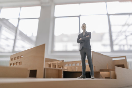 Miniature businessman figurine standing in architectural model