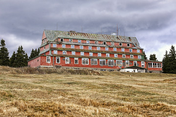 Large broken building of the unused hotel with red tiles facade