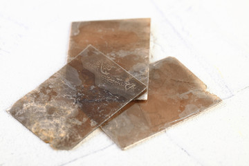 Natural mineral from geological collection - rough muscovite mica, common mica on white cement...