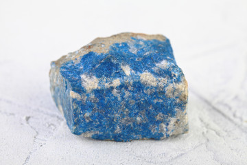 Natural mineral - rough Lazurite, Lapis Lazuli from Pamir, Tajikistan on white cement background.