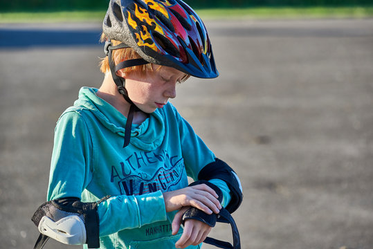 Boy wearing helmet putting on elbow pads