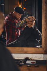 Caucasian boy getting haircut in barbershop indoor