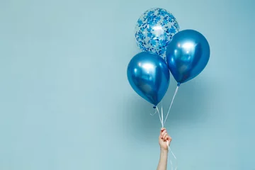  bright matte balloons on a blue background.  three blue inflated balloons. stylish party with balloons. round blue and transparent  balloon. Hand hold  balloon isolated  © mihail_pustovit