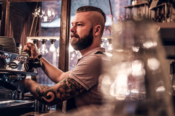 Fototapeta na wymiar Stylish barista looking sideways while preparing a cup of coffee for a customer in the coffee shop 
