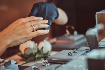 Girl tries on wedding ring in luxury jewelry store, hand close up